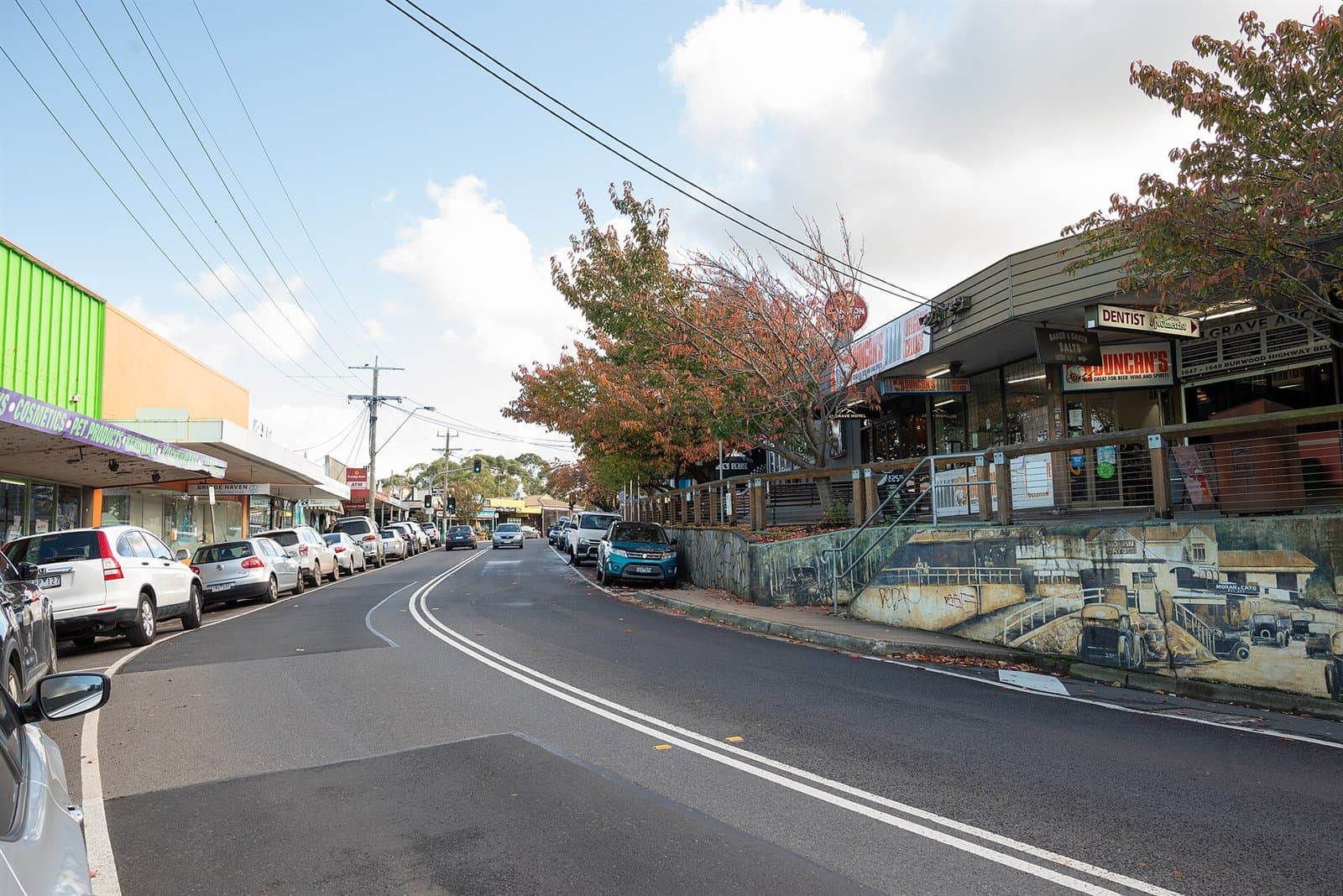 Shops along both sides of the Burwood Highway in Belgrave, with parked cars